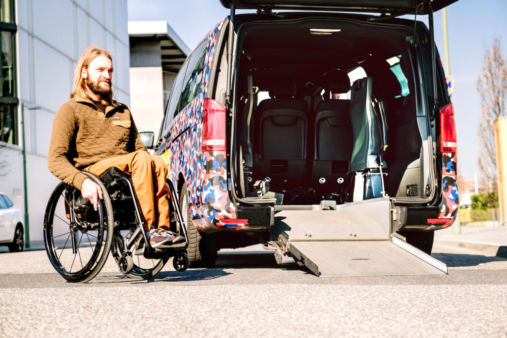 A young man in a wheelchair about to board a paratransit vehicle.