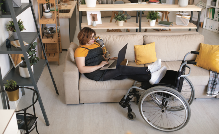 Young woman sitting on couch with her feet resting on her wheelchair.