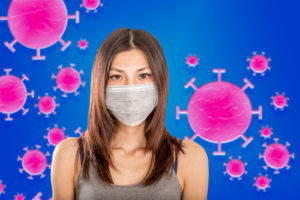 Woman wearing mask with a background of coronavirus germs.