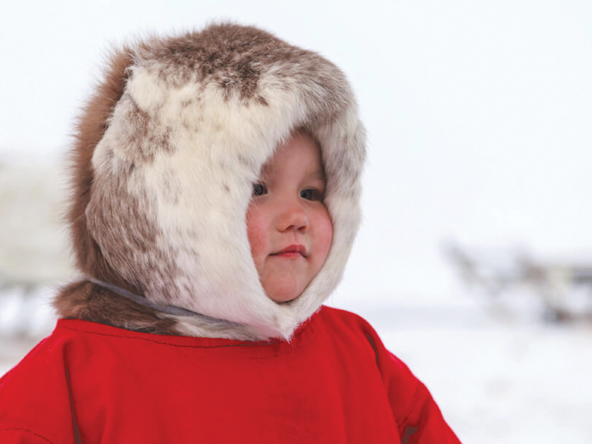 an infant inuit girl in a red coat with a fur hood